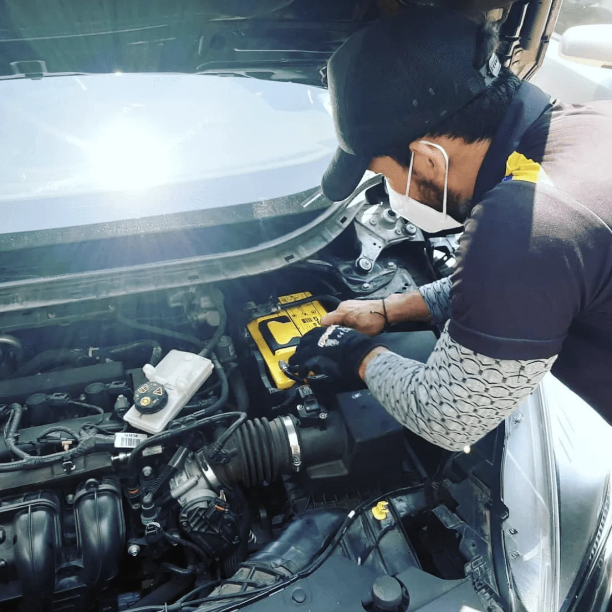 Técnico especializado instalando una batería a domicilio en el motor de un vehículo en Guayaquil.